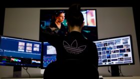 Pracownik przy biurku z trzema monitorami w studiu produkcji filmowej