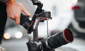 Operator trzyma profesjonalną kamerę filmową z teleobiektywem podczas produkcji
